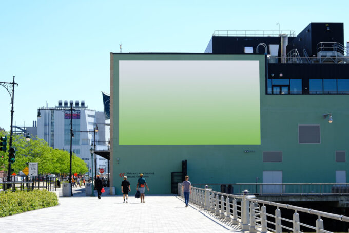 Side view of billboard on green brick wall.