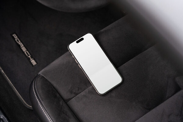 Side view of iPhone 15 Pro on an Alcantara car seat in a Porsche.
